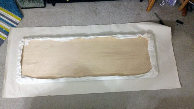 Lay canvas face down, smooth and center board batting side down