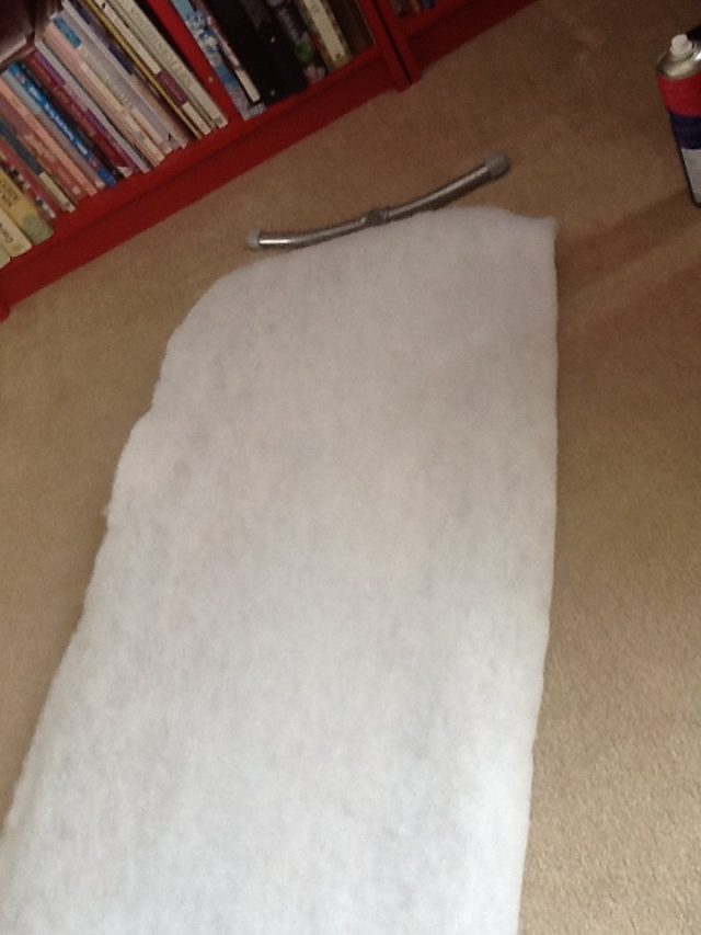 Pressboard being covered with batting